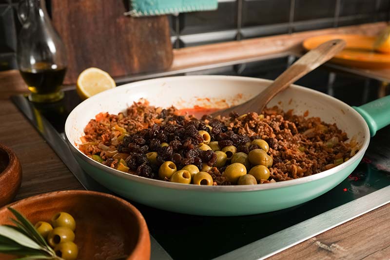 Oliven und Rosinen hinzugeben - Picadillo a la Habanera